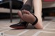 A woman wearing black stockings and high heels on a tiled floor.