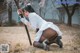 A woman in a white shirt and black stockings holding a sword.