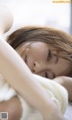 A young woman laying on a bed with her head on her hands.