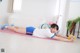 A woman laying on a pink yoga mat with a yellow ball.