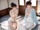A couple of women sitting on top of a wooden floor.