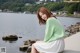 A woman sitting on a rock by the water.